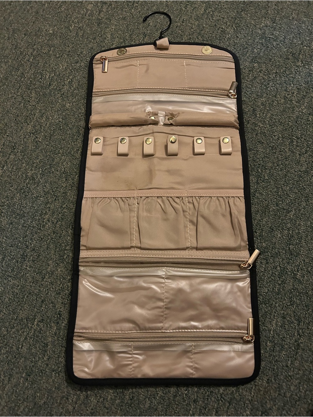 Trifold jewelry storage bag that unfolds w/ multiple pockets, zippers & hanger.